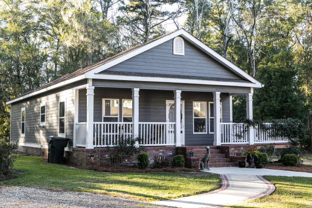 Small blue gray mobile home with a front and side porch. manufactured housing.