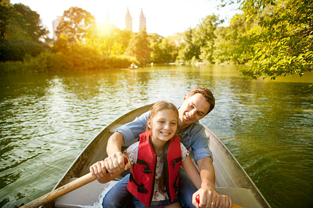 Father and daughter have fun outdoor rowing boat on lake