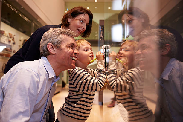 Family Looking At Artifacts In Glass Case On Trip To Museum