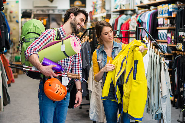 Man picking some hiking equipment, and asking a sales person about yellow jacket.