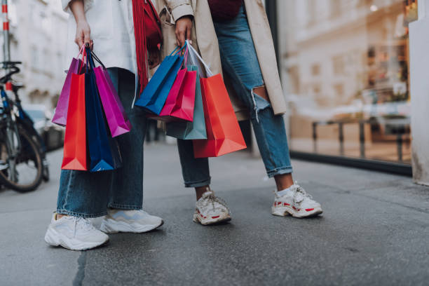 Look what we bought. Close up of two girl in jeans and sneakers holding colorful bags at fenton mi 48430