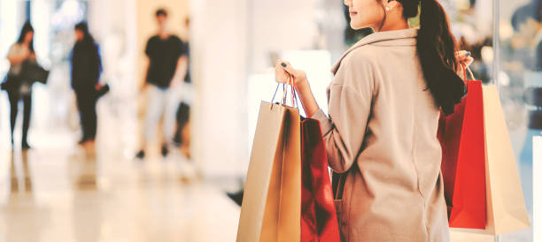 Lifestyle concept, Young happy asian woman with paper bag and coat in shopping mall, vintage style