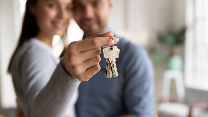 Close up happy young woman hugging man, holding keys