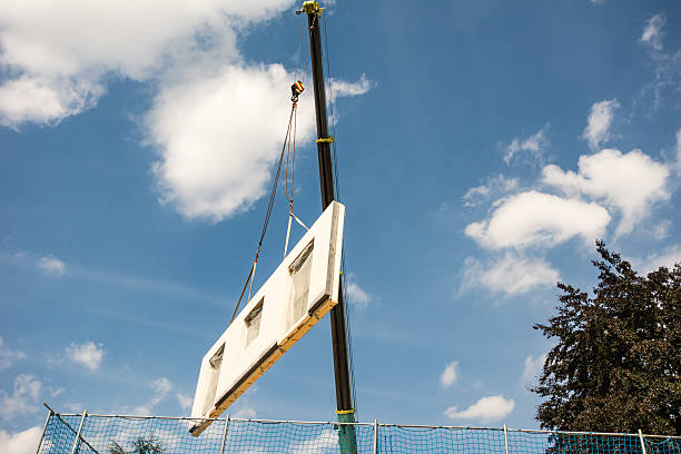 Assembling a prefabricated house - wall is hanging on a crane