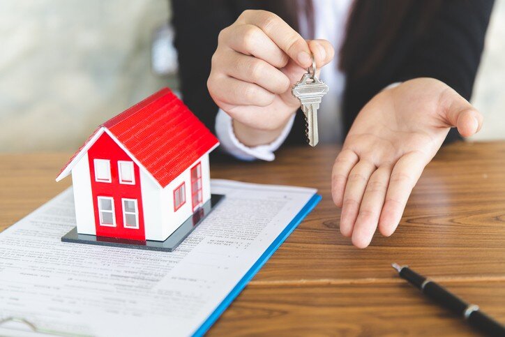 Your new house, real estate agent holding house key to his client after signing contract agreement in office,concept for real estate, renting property