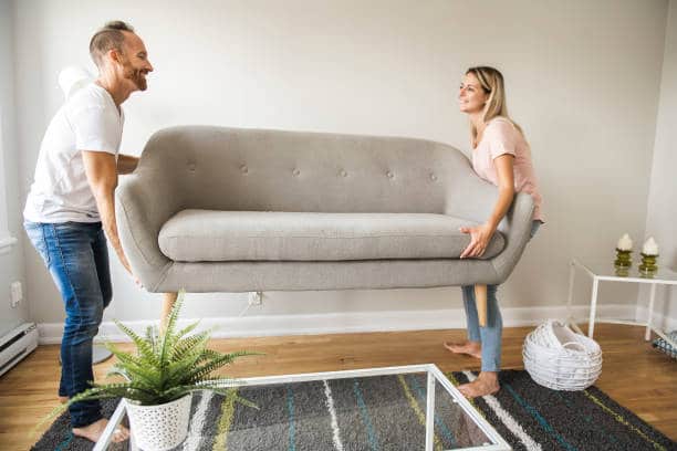 A Full length of happy couple placing home furnishings in living room of new home in fenton mi 48430