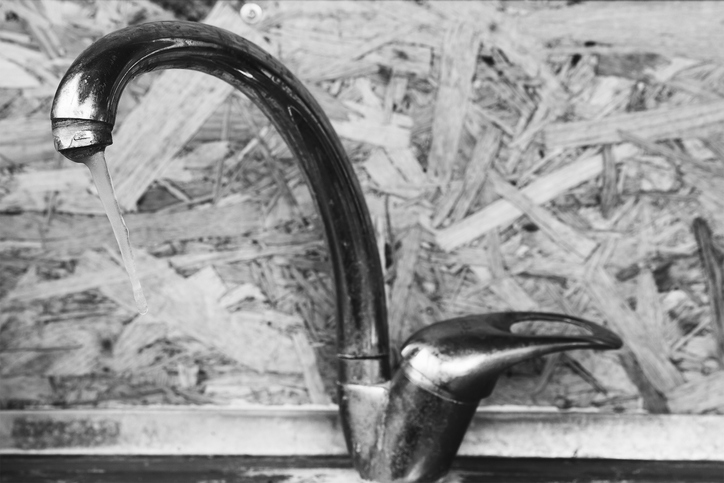 icicle on the frozen water tap closeup indoors, selective focus, black and white photo